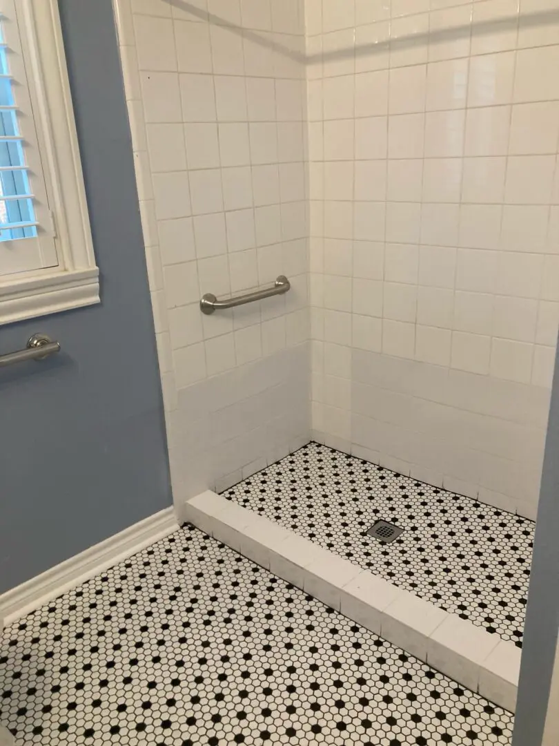 A shower area with white tiles as walls