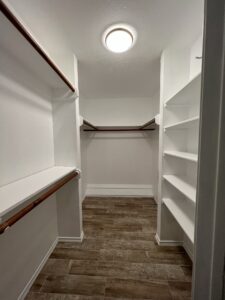 A walk in closet with shelves and a shelf above it.